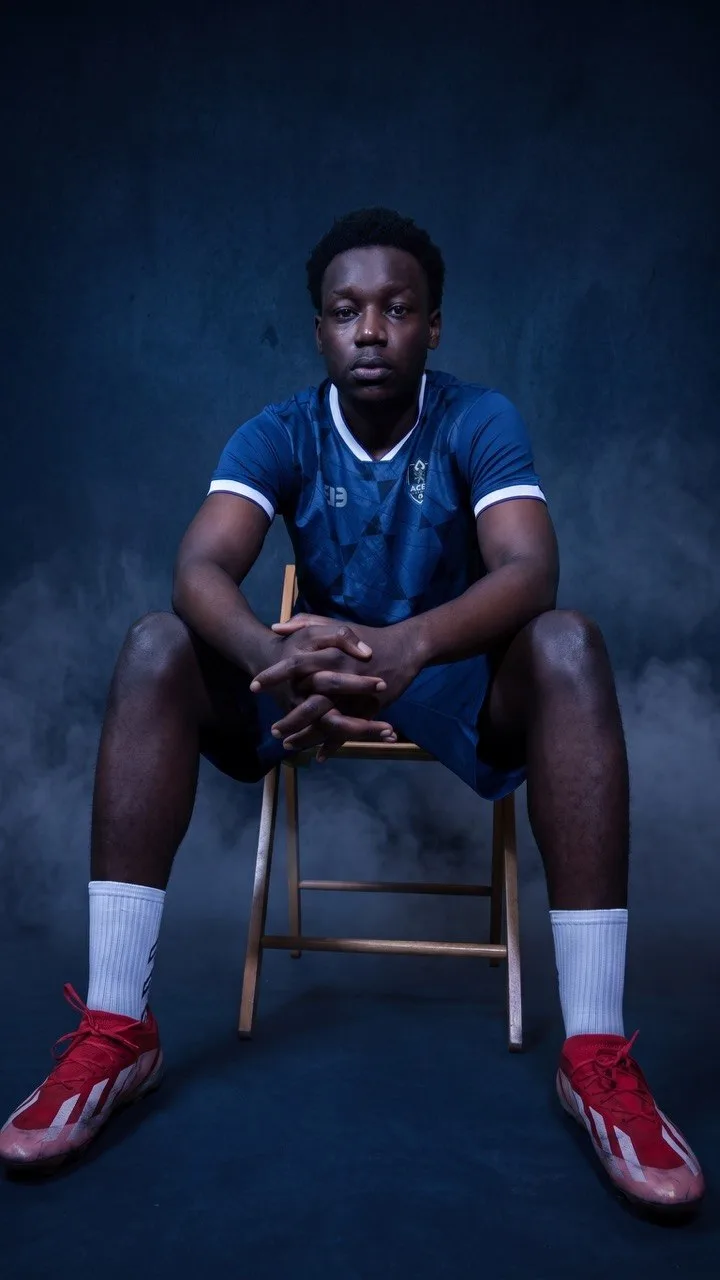 An Aces FC player seated on a stool in the club's blue home kit.