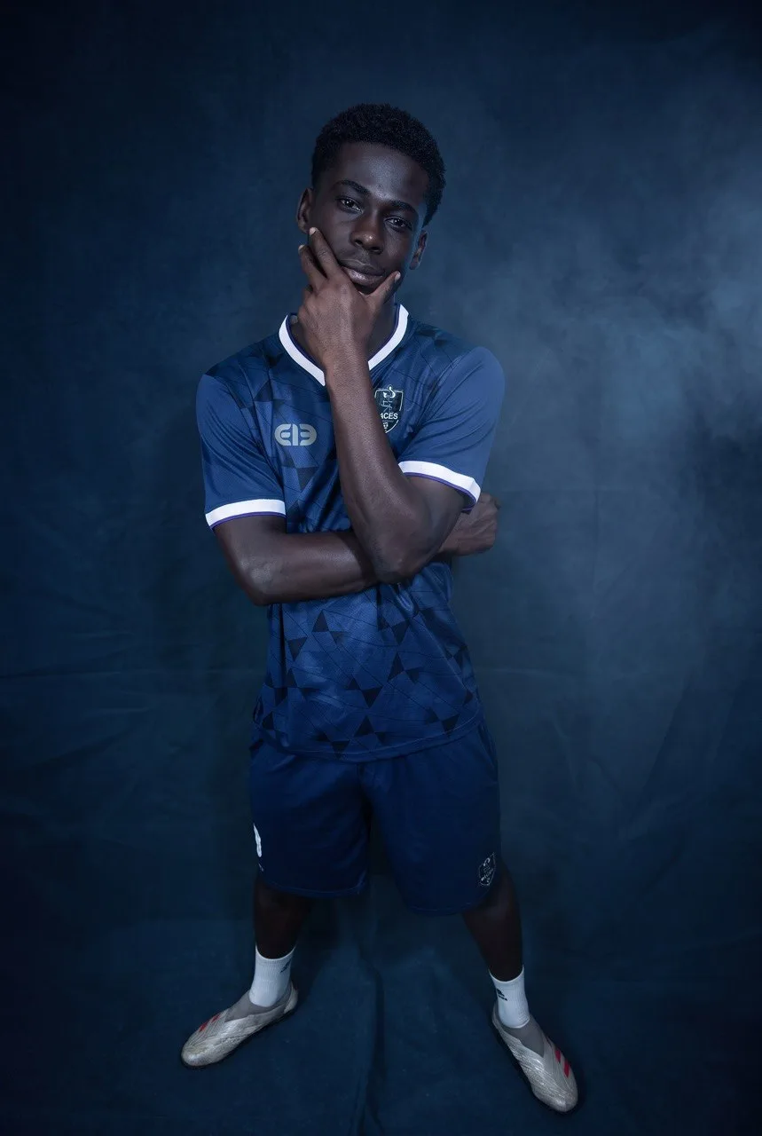 An Aces FC player standing in the club's blue home kit, studio portrait.